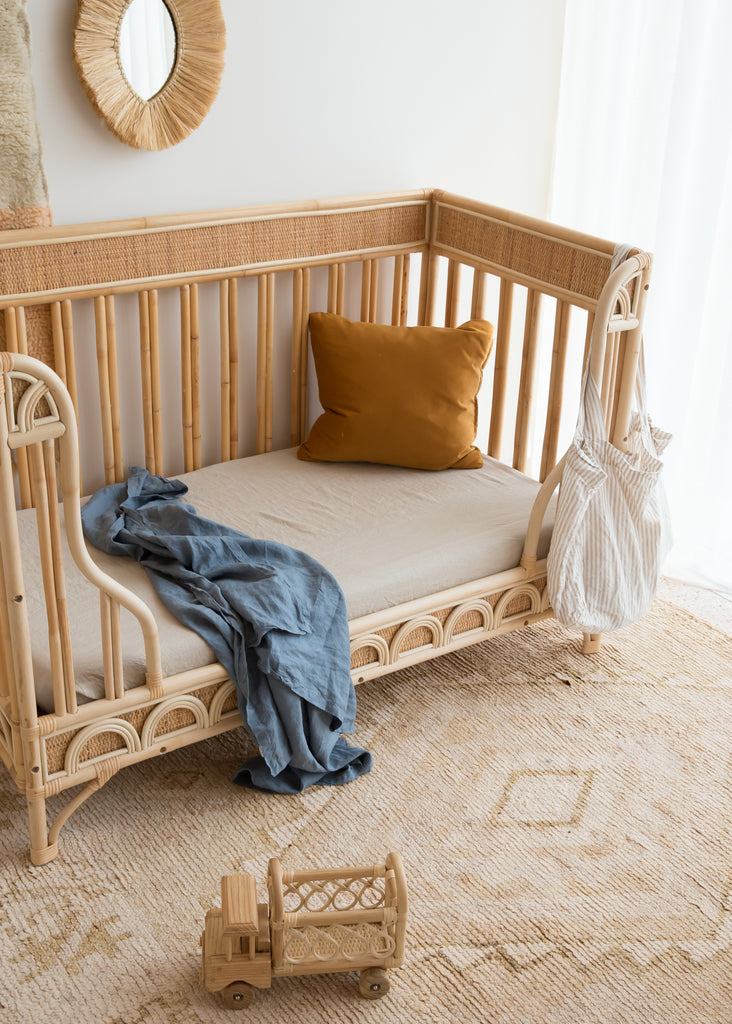 Natural Linen Cot Sheet with a Lake Blue swaddle draped over the cot 