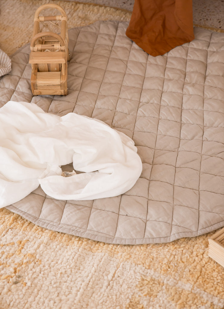 Natural Linen Plat Mat with wooden toys and linen swaddles placed on top 